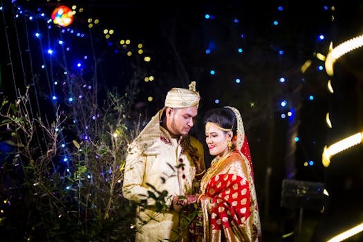 Beautiful couple enjoying their wedding night in traditional attire, surrounded by colorful lights.